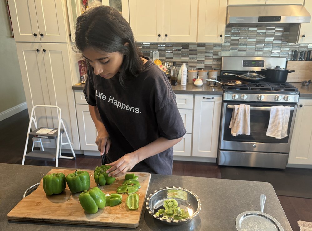 A CARES member chopping green bell peppers in a kitchen