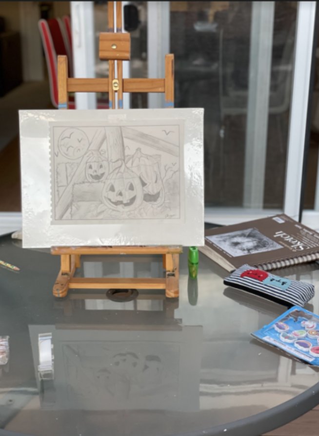 A pencil drawing of Halloween pumpkins displayed on a small easel