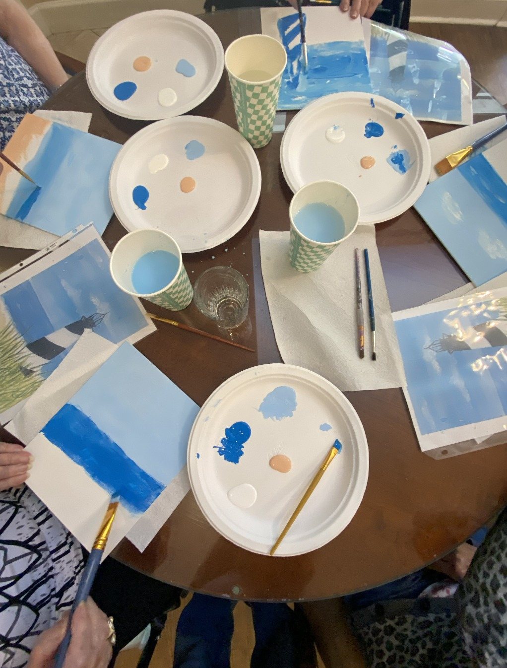 Paint palettes and half-finished blue sky paintings on a table