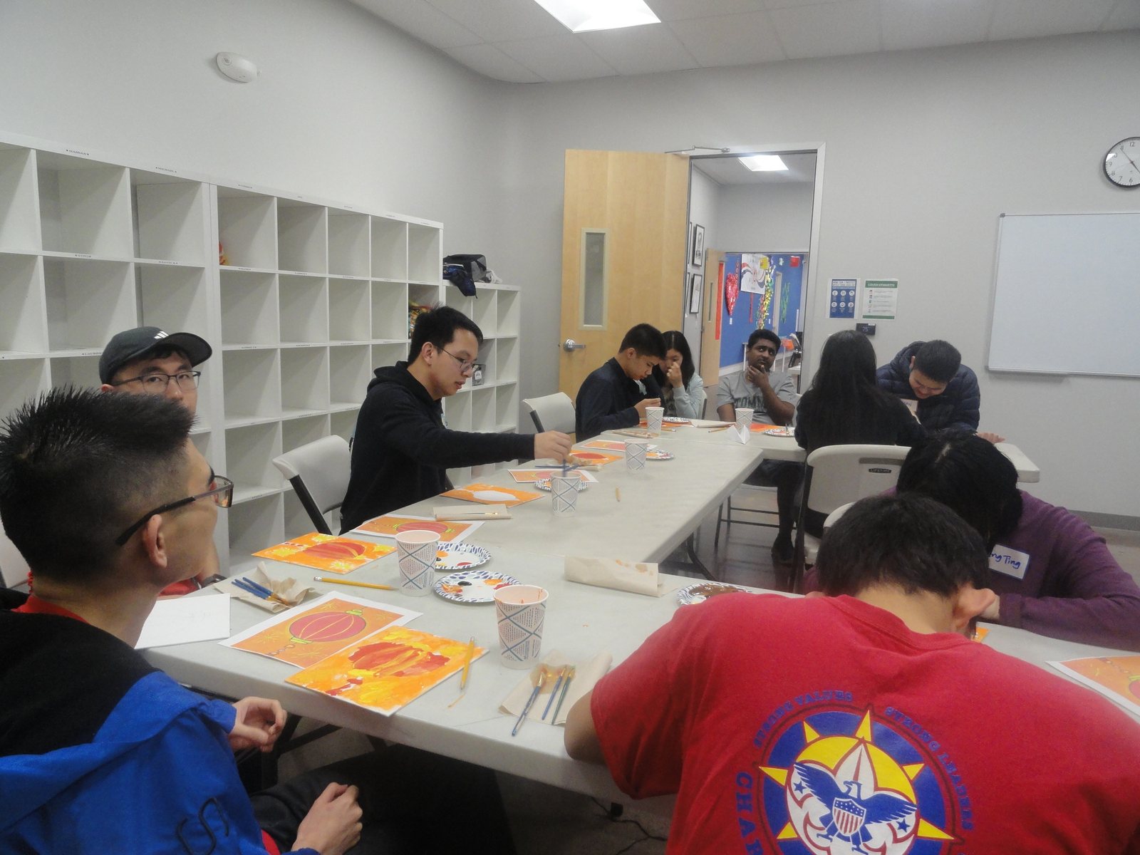 Participants painting red lanterns at a long table