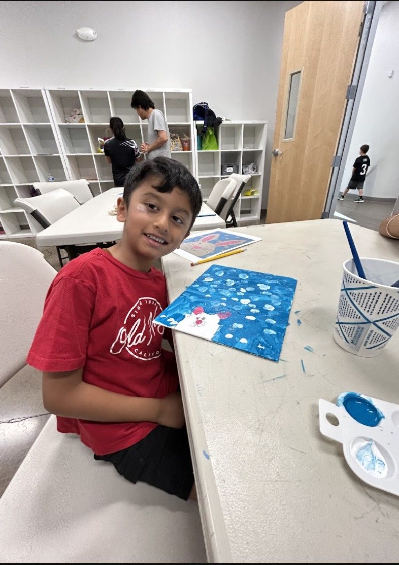 A participant smiling next to his bunny painting in progress