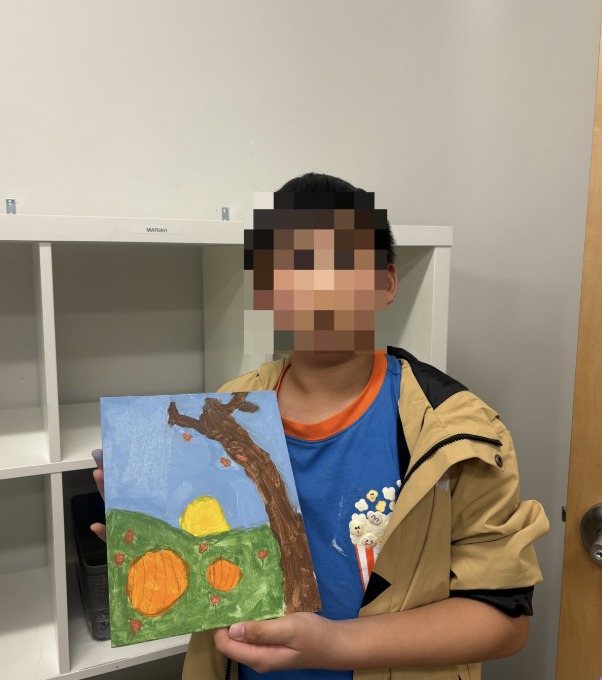 A participant holding up his autumn tree painting