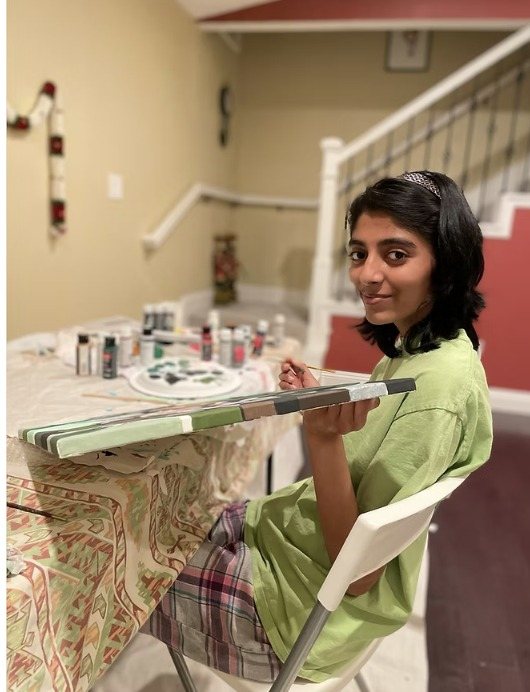 A CARES officer holding a canvas while painting