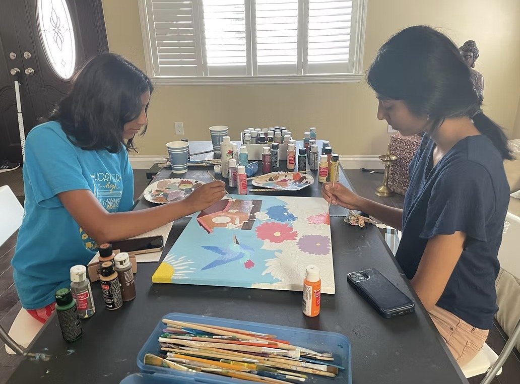 Two CARES officers painting at a table covered with paint
