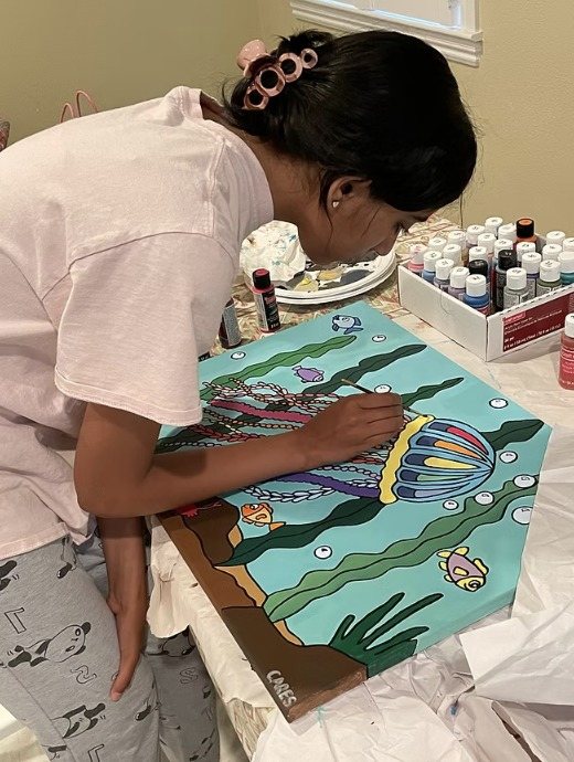 A CARES officer painting an underwater jellyfish scene