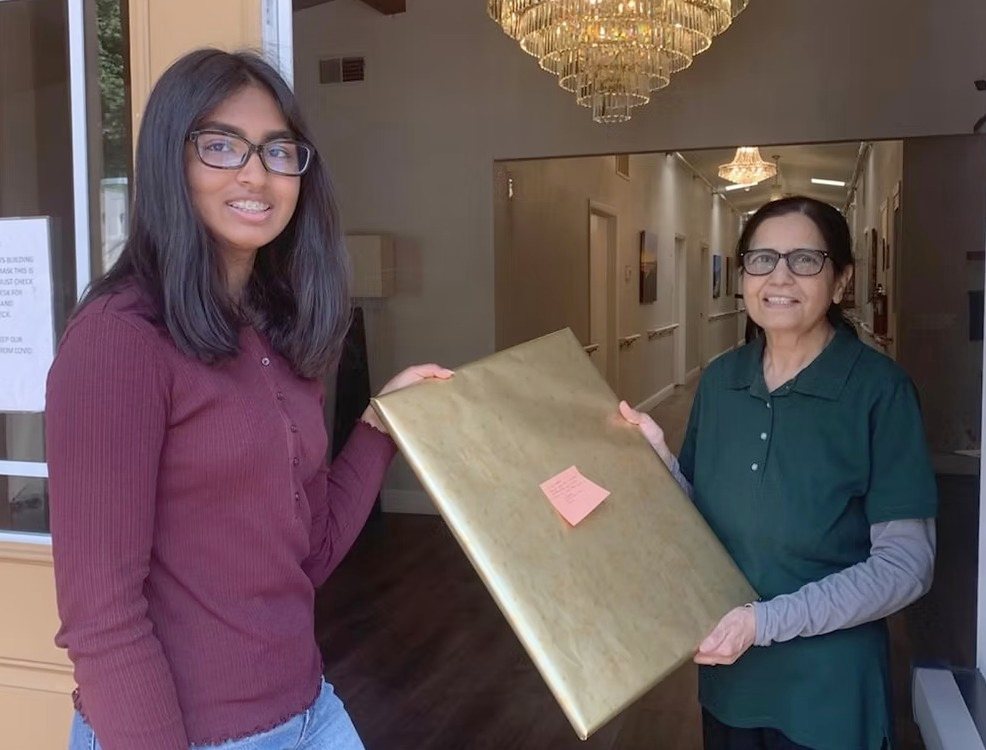 A CARES officer handing the wrapped painting to a Marin Terrace staff member