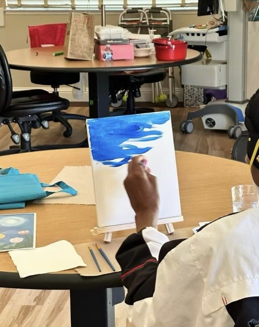 A resident painting a blue ocean on an easel