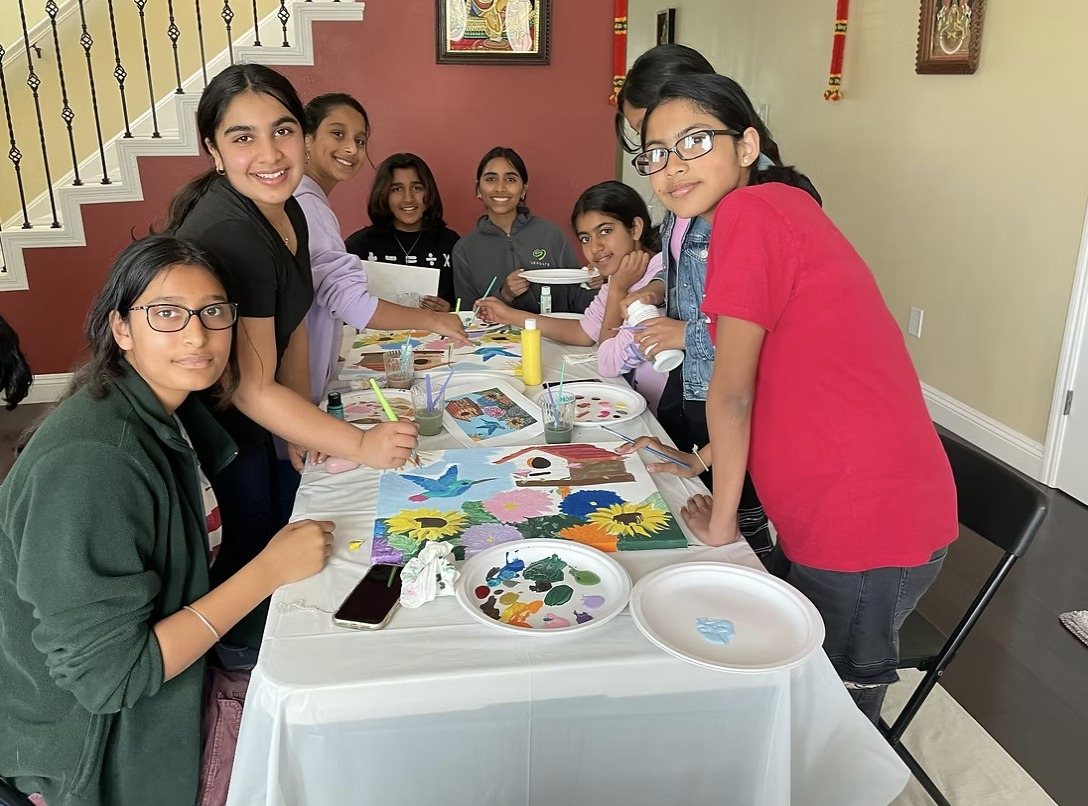Troop members painting at a table with paint palettes