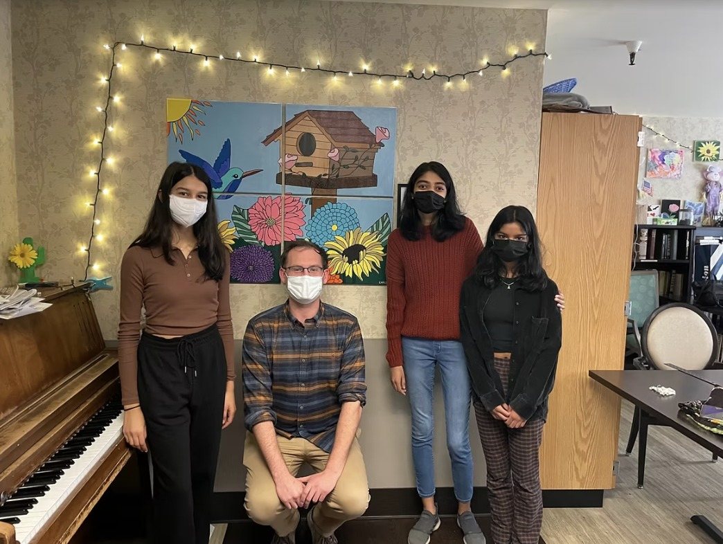 CARES officers and a staff member standing beside the hung painting "Burst of Blooms"