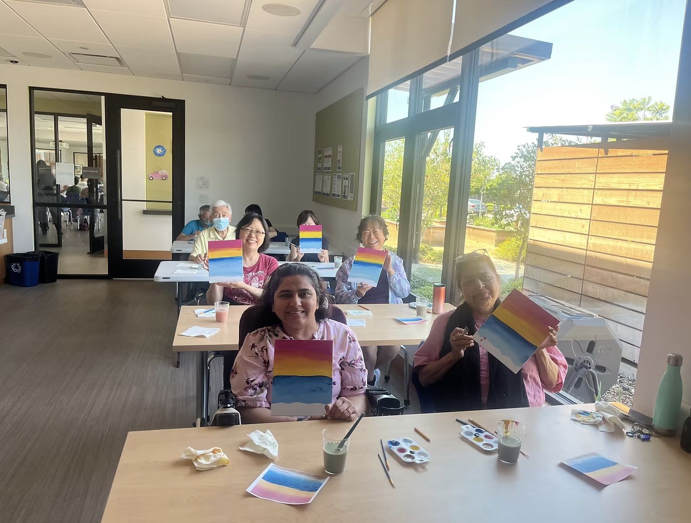 Participants smiling and holding up their sunset paintings